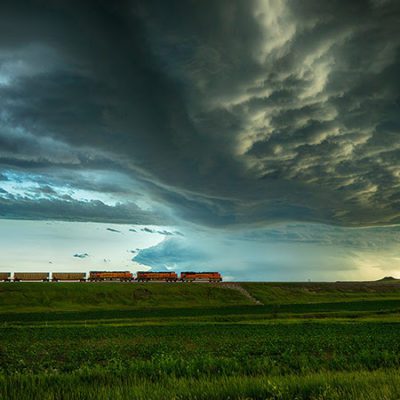 Empty coal unit train rolls through plains under an ominous sky