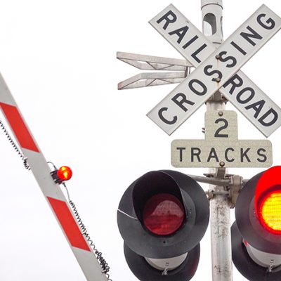 CLOSE UP: Railway crossing sign with flashing red lights and gates closing